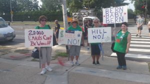 A group of people holding signs on the side walk